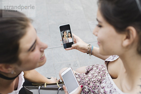 Zwei junge Frauen beim Betrachten von Fotos auf dem Handy