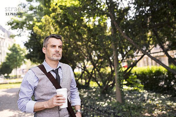 Erwachsener Geschäftsmann mit Kaffee im Stadtpark