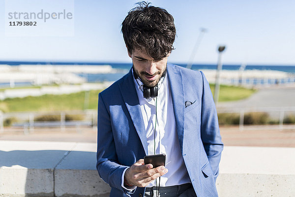 Junger Geschäftsmann beim Blick auf das Smartphone im Freien