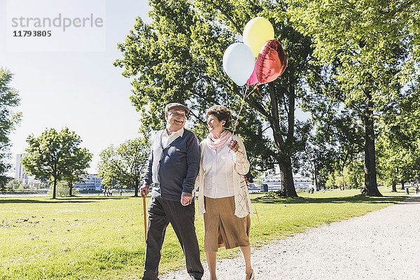 Glückliches Seniorenpaar mit Luftballons im Park