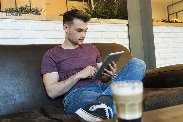 Junger Mann mit Tablette in einem Cafe