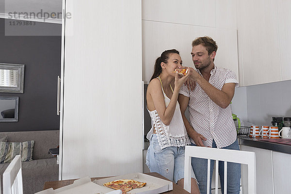 Junges Paar beim Pizzaessen in der Küche