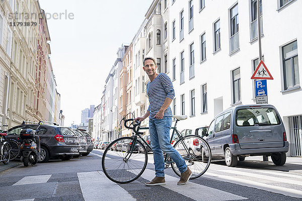 Porträt eines lächelnden reifen Mannes mit Fahrrad über die Straße