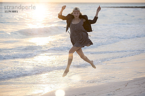 Junge Frau springt vor Freude am Strand