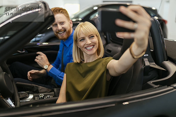 Paar  das sich selbst nimmt  sitzt im Cabrio im Autohaus