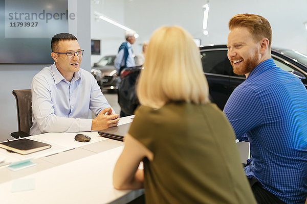 Verkäufer berät Ehepaar im Autohaus