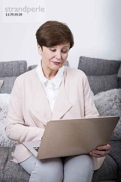 Seniorin auf der Couch sitzend  mit Laptop