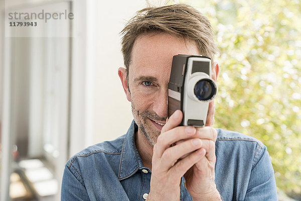 Porträt eines lächelnden Mannes mit Filmkamera beim Betrachter