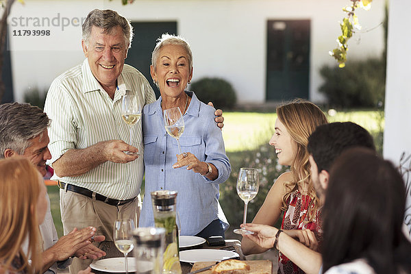 Fröhliches Seniorenpaar mit Familie beim gemeinsamen Mittagessen im Freien