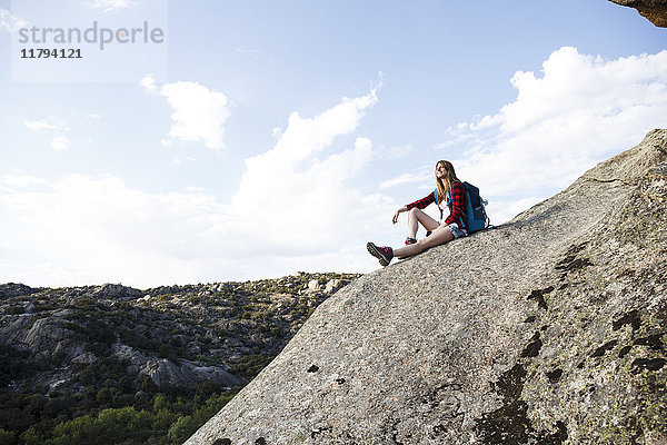 Spanien  Madrid  junge Frau auf einem Felsen während eines Trekking-Tages