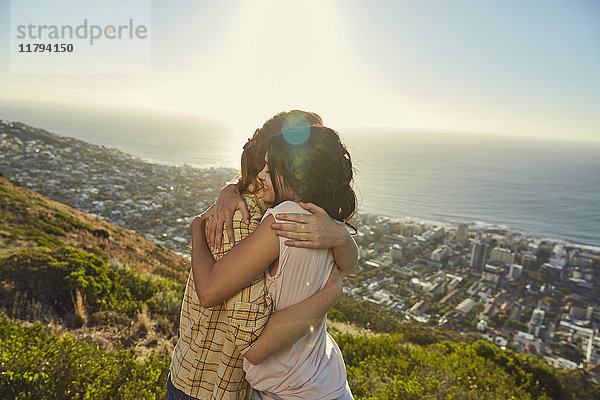 Südafrika  Kapstadt  Signal Hill  zwei junge Frauen  die sich über der Stadt umarmen