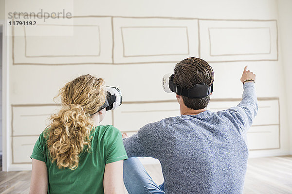 Junges Paar in neuem Zuhause mit VR-Brille denkt über Innenarchitektur nach