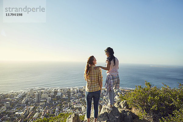 Südafrika  Kapstadt  Signal Hill  zwei junge Frauen mit Blick auf die Stadt und das Meer