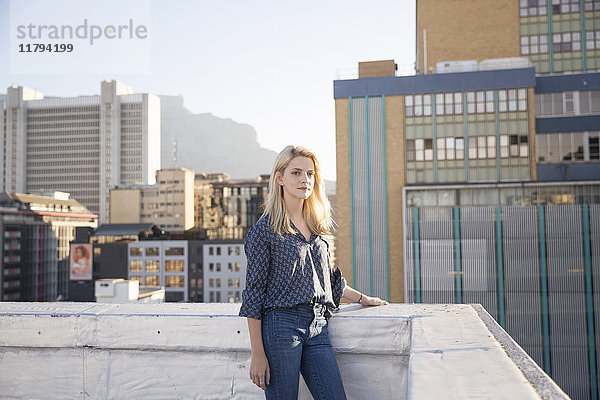 Junge Frau steht auf einer Dachterrasse