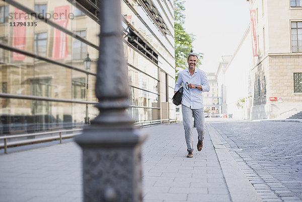 Lächelnder Mann  der in der Stadt spazieren geht.
