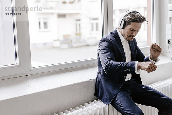 Leidenschaftlicher Geschäftsmann beim Hören von Musik über Kopfhörer