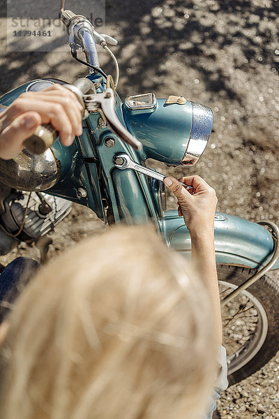 Frau repariert Oldtimer-Motorrad