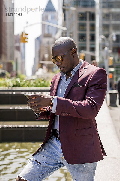USA  New York City  Manhattan  stilvoller Geschäftsmann mit Blick auf Smartphone