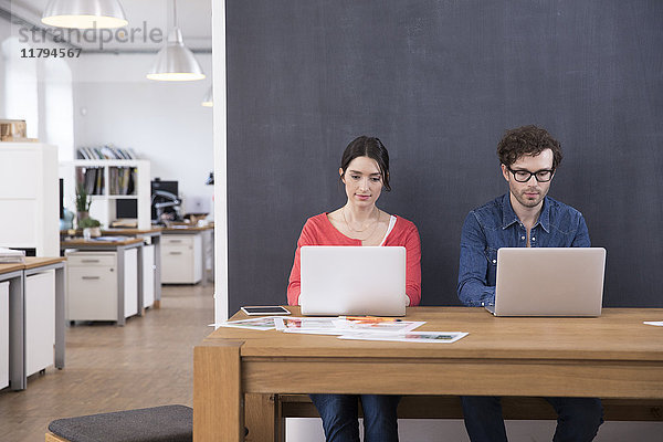 Mann und Frau mit Laptops auf dem Tisch im Büro