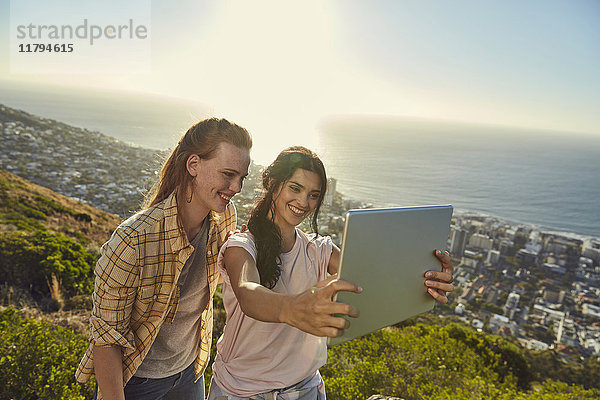 Südafrika  Kapstadt  Signal Hill  zwei junge Frauen über der Stadt  die einen Selfie mit Tablette nehmen.