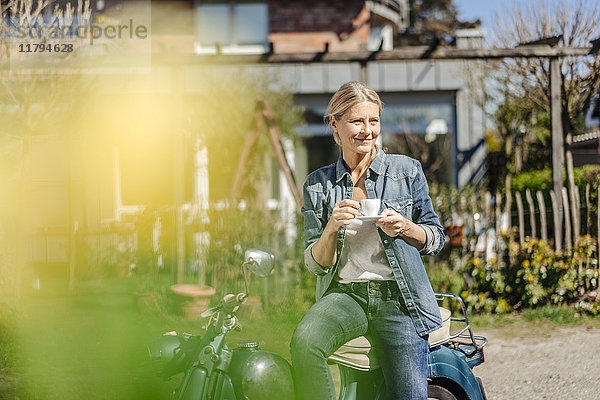 Lächelnde Frau auf Oldtimer-Motorrad bei einer Kaffeepause