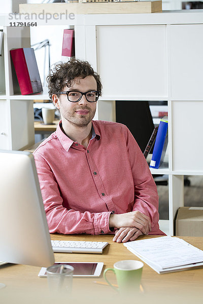 Porträt eines selbstbewussten Mannes am Schreibtisch im Büro