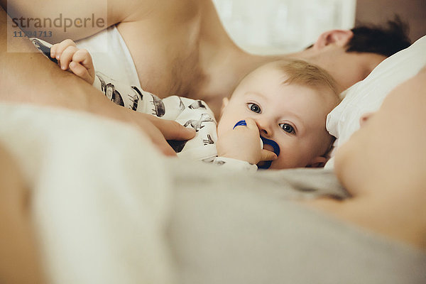 Baby Junge kuschelt mit Eltern im Bett