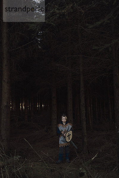Kleiner Junge im Wald stehend in Ritterkostüm