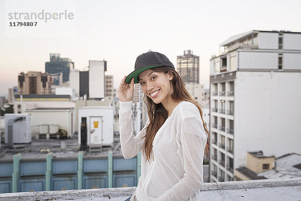 Junge Frau auf einer Dachterrasse stehend  lächelnd