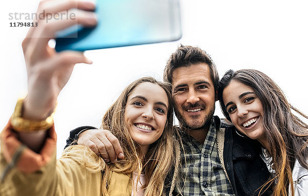 Drei Freunde nehmen einen Selfie mit nach draußen.