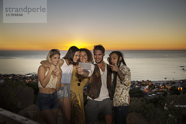 Junge Leute  die einen Selfie an der Küste zum Sonnenuntergang nehmen