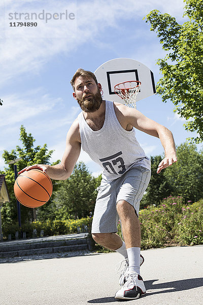 Mann spielt Basketball auf dem Freigelände
