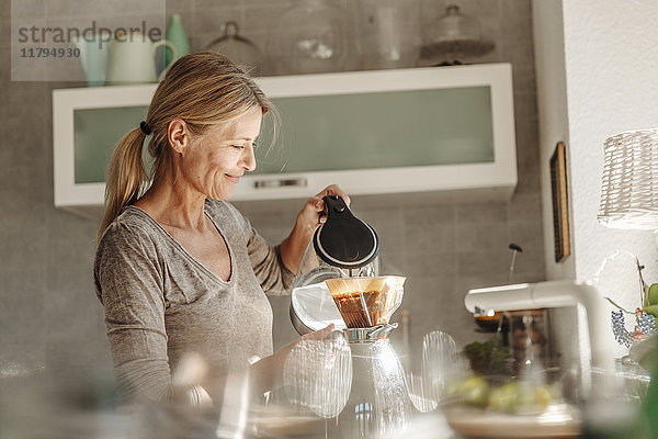 Frau zu Hause in der Küche bei der Kaffeezubereitung