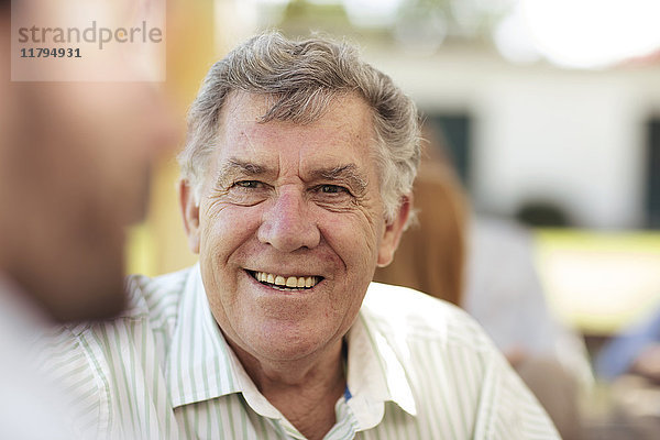 Lächelnder älterer Mann  der sich auf einer Gartenparty trifft.