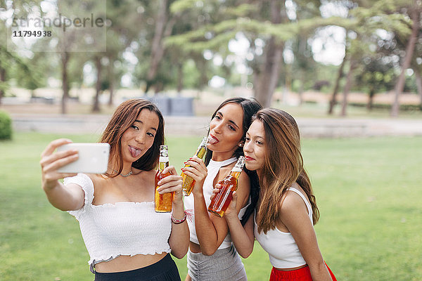 Verspielte Freunde im Park  die Bier trinken und einen Selfie nehmen