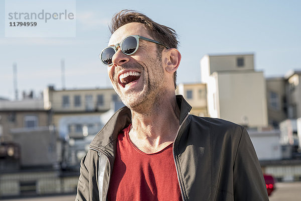 Porträt des lachenden  reifen Mannes mit Stoppeln und Sonnenbrille