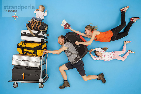 Familie mit Gepäckwagen eilt zur Abreise