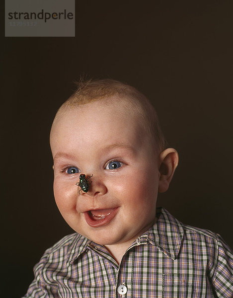 Porträt des aufgeregten Jungen mit Spielzeugfliege auf der Nase
