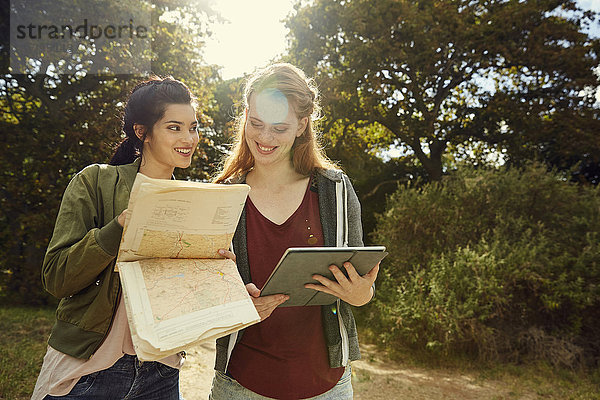 Zwei junge Frauen mit Tablette und Karte in der Natur