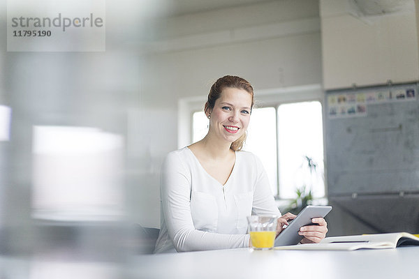 Geschäftsfrau  die am Schreibtisch in ihrem Büro arbeitet  mit Hilfe eines digitalen Tabletts.