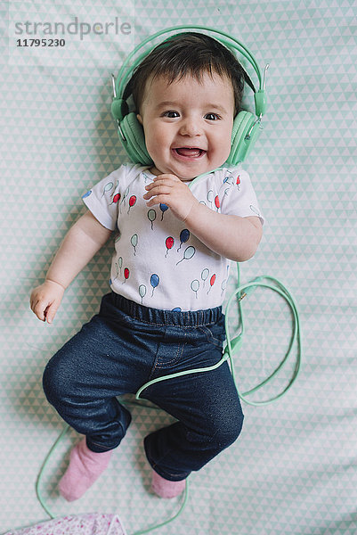 Portrait des glücklichen Mädchens mit Kopfhörer auf der Decke liegend