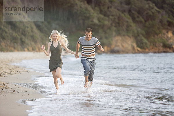 Glückliches Paar  das am Strand läuft
