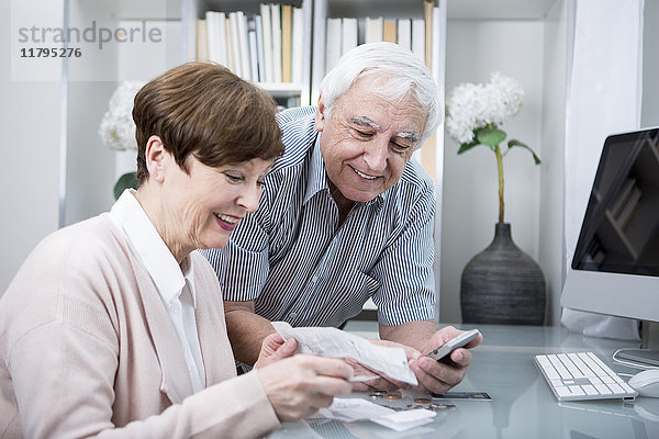 Seniorenpaar mit Rechnungen und Taschenrechner zur Kontrolle der Ausgaben