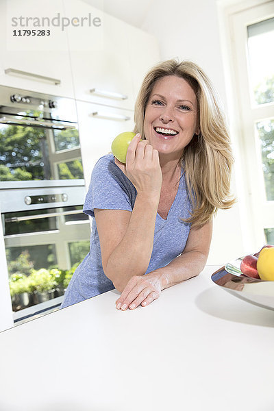 Porträt einer glücklichen Frau zu Hause beim Apfelessen