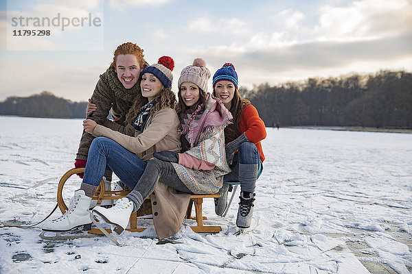 Freunde beim Schlittenfahren auf dem zugefrorenen See
