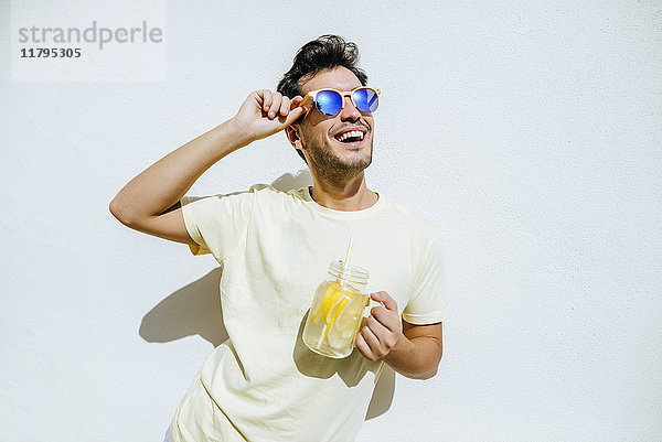 Jung und mit Sonnenbrille und Limonade in weißer Vorderwand