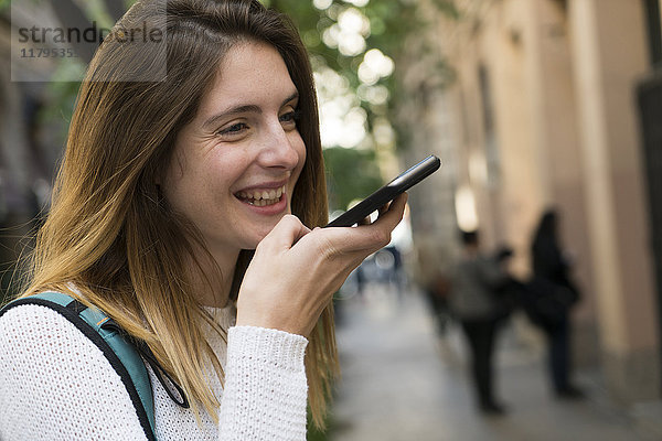 Glückliche junge Frau mit Handy in der Stadt