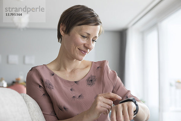Porträt einer lächelnden Frau mit smartwatch zu Hause
