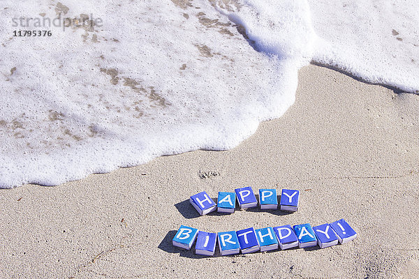 Briefe auf Streichholzschachteln  die das Wort Happy Birthday am Strand bilden.