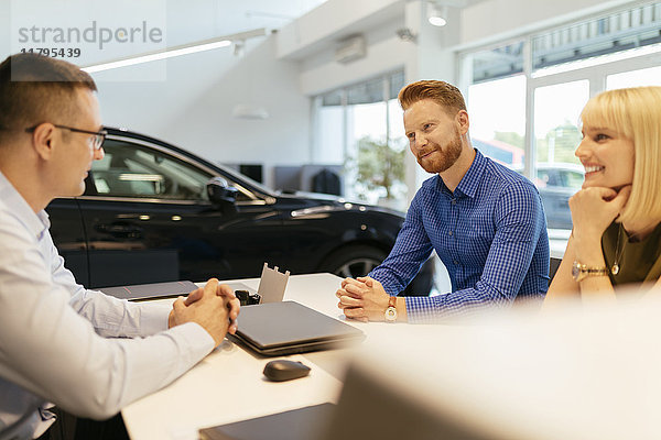 Verkäufer berät Ehepaar im Autohaus